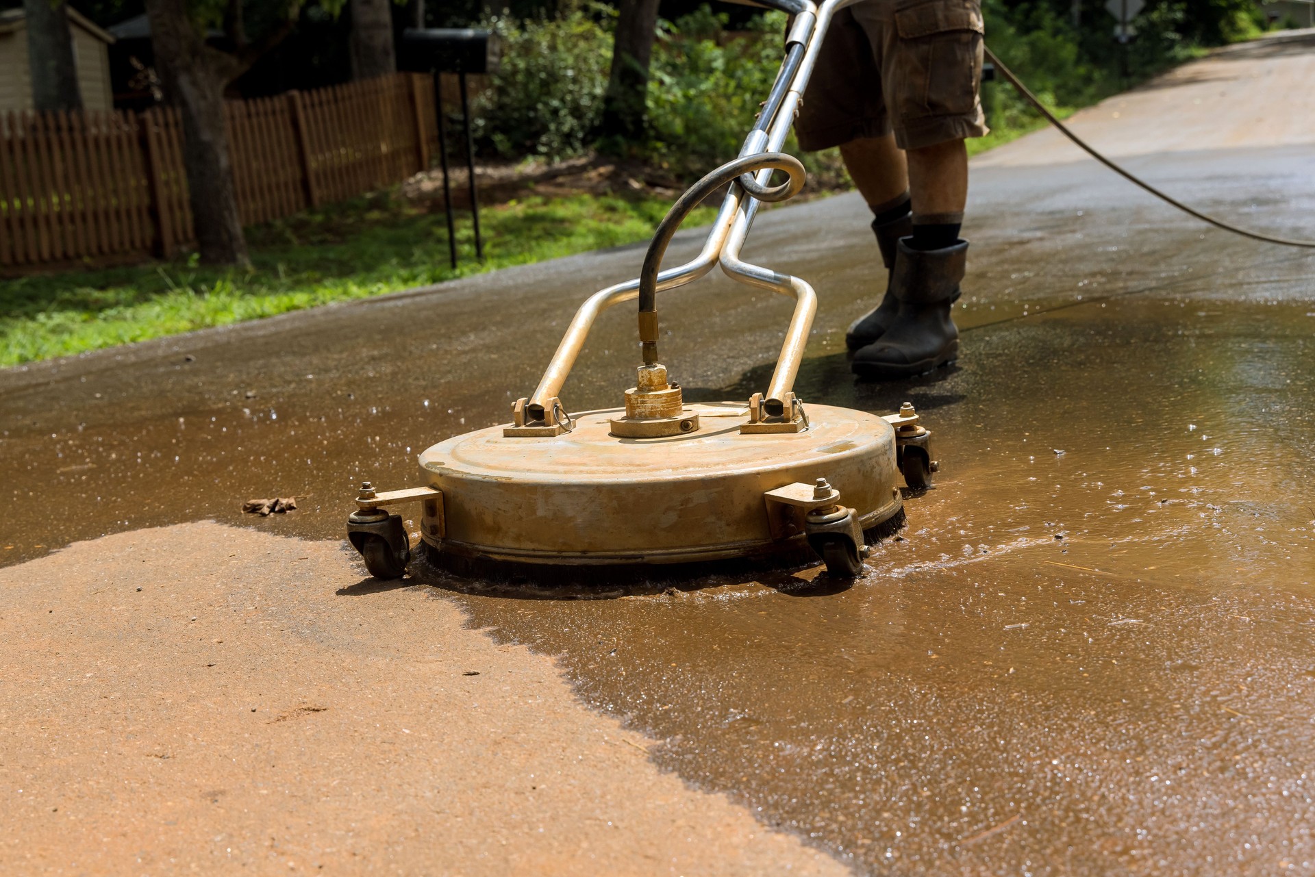 Using a cleaning machine, a worker cleans the street with the help of a used high pressure washing machine